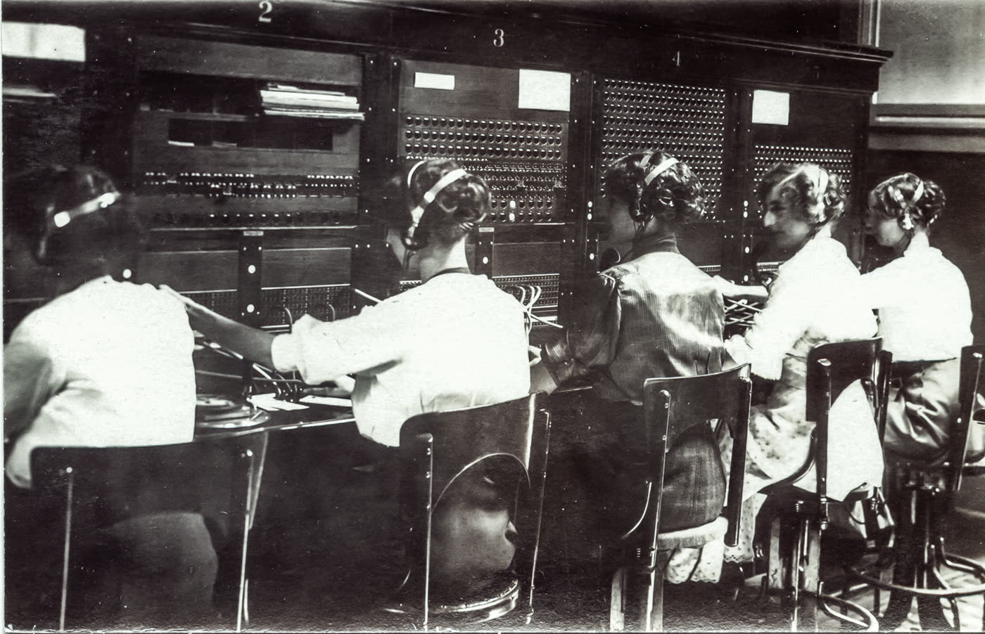 Telephone operators connecting calls by hand at a switchboard, early twentieth century